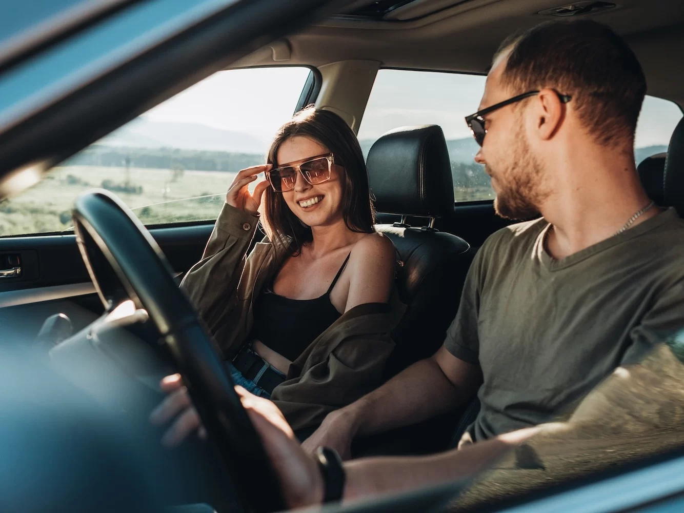 Jeune couple souriant dans une voiture en pleine nature, prêt à vivre un road trip au Costa Rica.